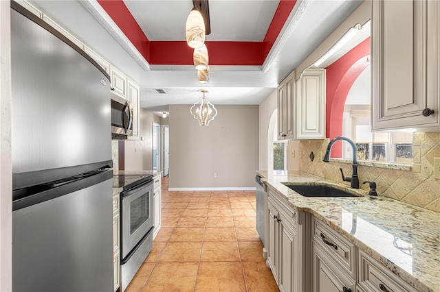 kitchen featuring appliances with stainless steel finishes, light tile patterned floors, sink, decorative light fixtures, and a raised ceiling