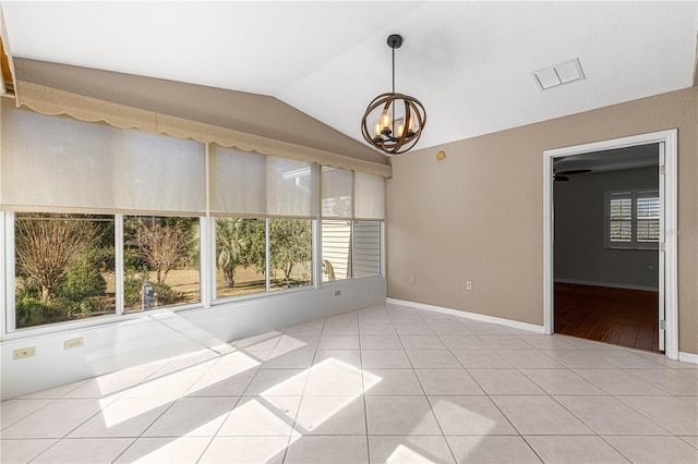 tiled empty room featuring vaulted ceiling, a chandelier, and a healthy amount of sunlight