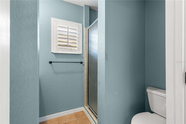 bathroom featuring toilet, tile patterned floors, and a shower with door