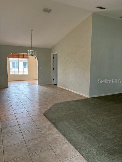 spare room featuring vaulted ceiling and light tile patterned flooring