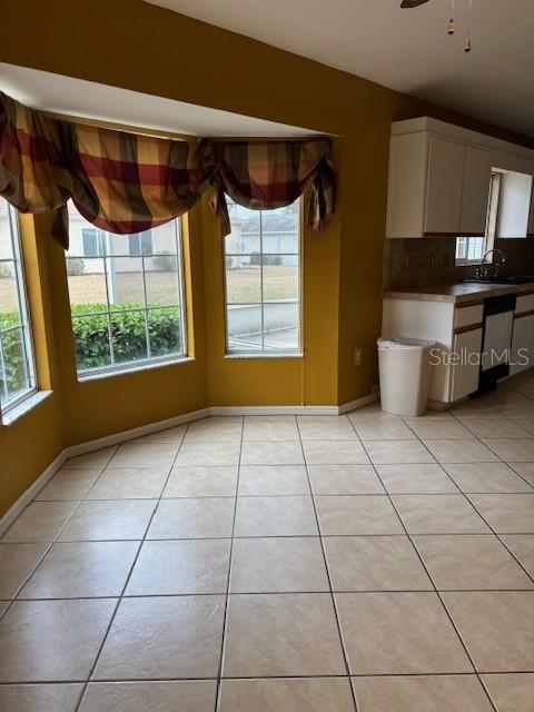 unfurnished dining area featuring sink, ceiling fan, and light tile patterned flooring