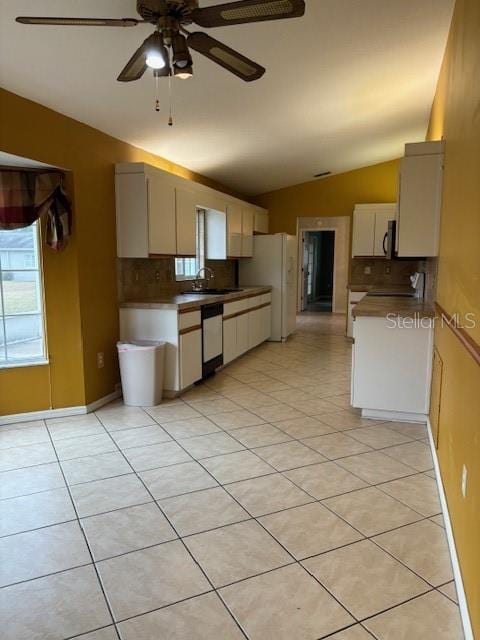 kitchen with sink, tasteful backsplash, vaulted ceiling, light tile patterned floors, and dishwasher