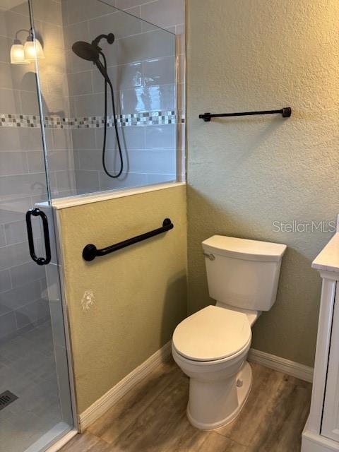 bathroom featuring vanity, toilet, hardwood / wood-style floors, and a shower with shower door