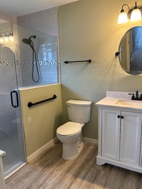 bathroom with hardwood / wood-style flooring, vanity, toilet, and walk in shower