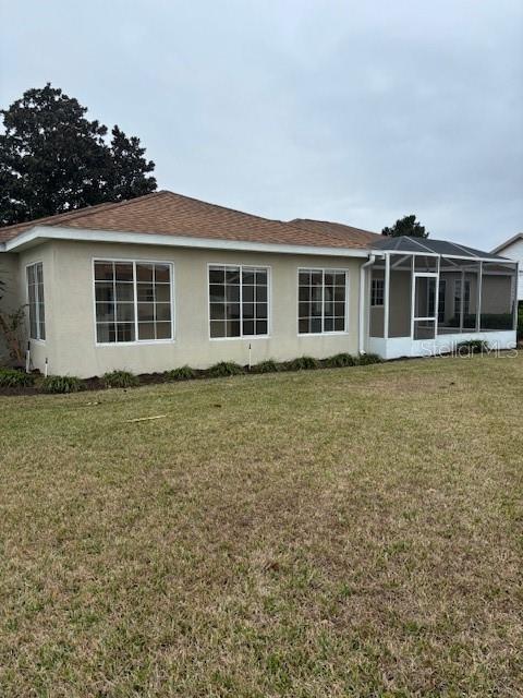 rear view of property with a lanai and a lawn