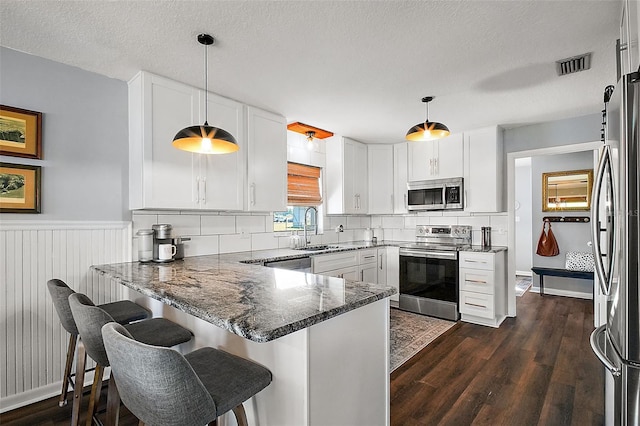 kitchen featuring hanging light fixtures, kitchen peninsula, appliances with stainless steel finishes, and sink