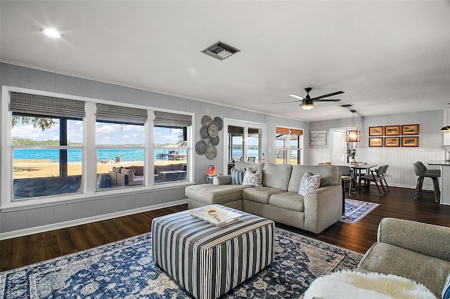 living room with ceiling fan, a wealth of natural light, dark hardwood / wood-style flooring, and a water view