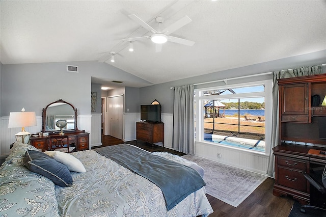 bedroom with a textured ceiling, lofted ceiling, dark hardwood / wood-style flooring, rail lighting, and ceiling fan