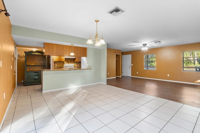 unfurnished living room featuring light tile patterned floors and ceiling fan with notable chandelier