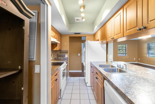 kitchen with a tray ceiling, sink, white appliances, and light tile patterned floors