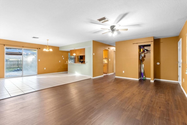 unfurnished living room with ceiling fan with notable chandelier and wood-type flooring