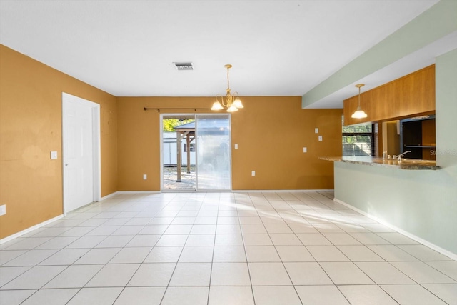 unfurnished room with a chandelier and light tile patterned flooring