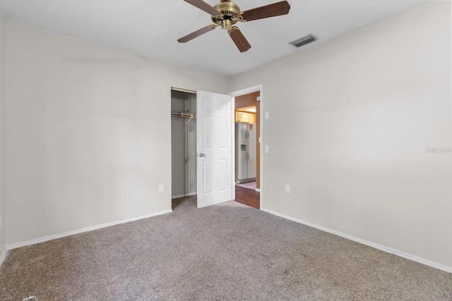 unfurnished bedroom featuring stainless steel fridge with ice dispenser, a closet, carpet, and ceiling fan