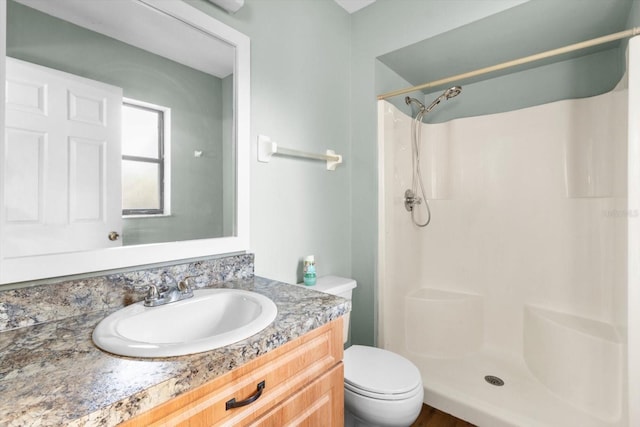 bathroom featuring toilet, walk in shower, and vanity