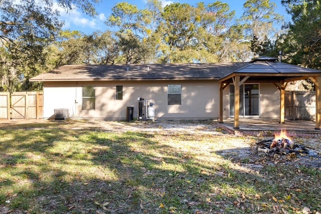 back of house featuring a gazebo, a yard, central air condition unit, and a fire pit