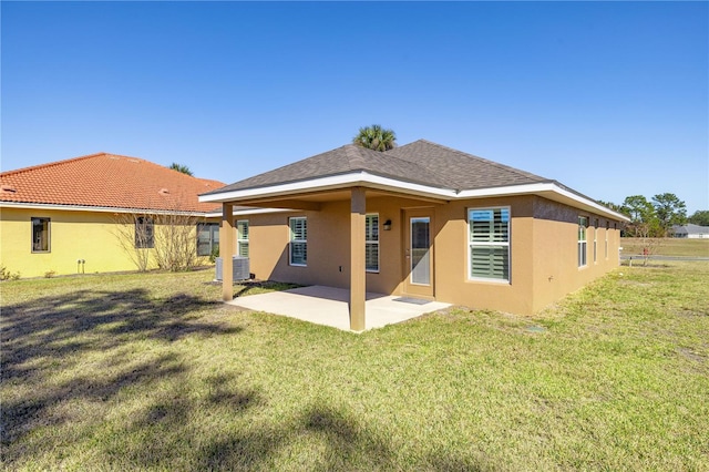 back of house with central AC unit, a lawn, and a patio