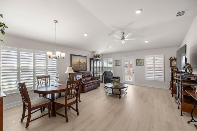 dining space featuring vaulted ceiling, ceiling fan with notable chandelier, and light hardwood / wood-style floors