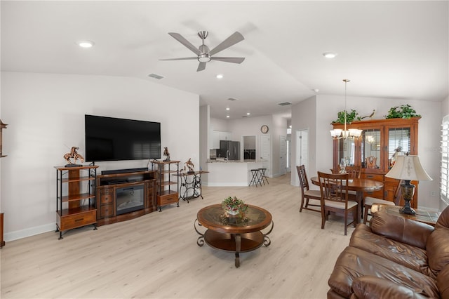 living room featuring ceiling fan with notable chandelier, lofted ceiling, and light hardwood / wood-style floors