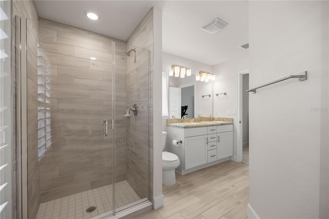 bathroom with toilet, vanity, and an enclosed shower