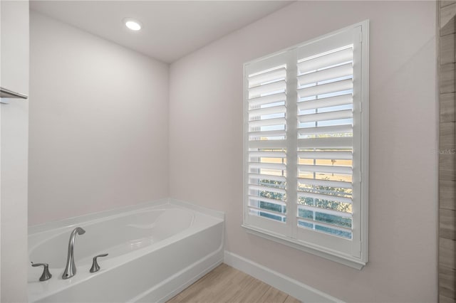 bathroom with a tub and hardwood / wood-style flooring