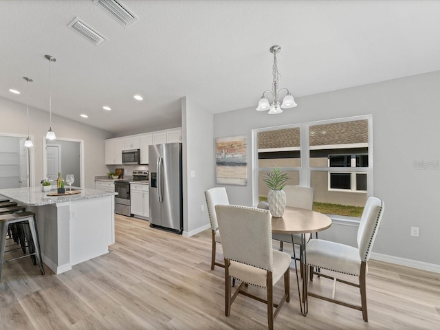 dining room featuring a wealth of natural light, light wood-type flooring, a notable chandelier, and vaulted ceiling