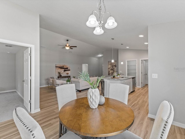 dining space featuring sink, light hardwood / wood-style floors, ceiling fan with notable chandelier, and lofted ceiling