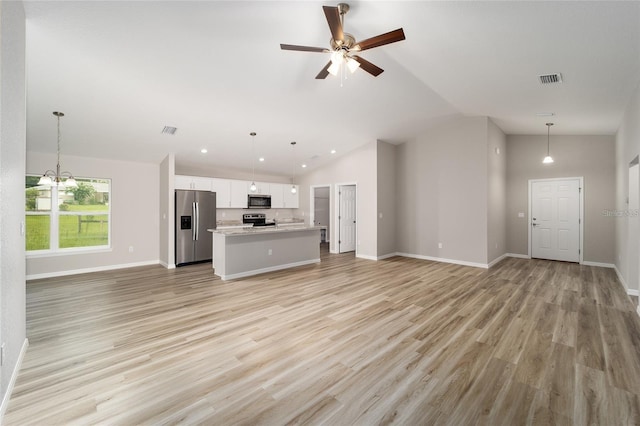 unfurnished living room with ceiling fan with notable chandelier, light hardwood / wood-style floors, and high vaulted ceiling