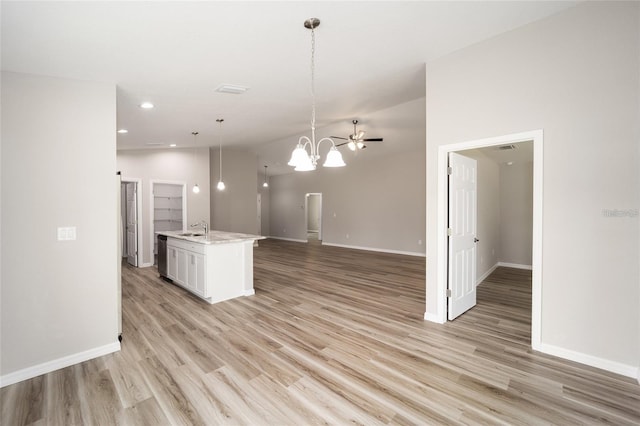 kitchen featuring decorative light fixtures, sink, white cabinetry, a notable chandelier, and an island with sink