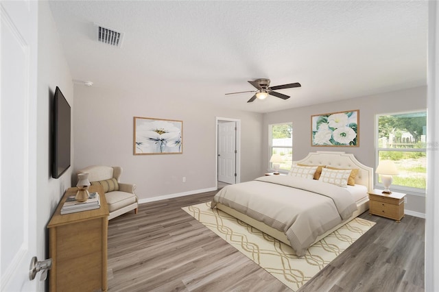 bedroom with a textured ceiling, ceiling fan, and dark hardwood / wood-style flooring