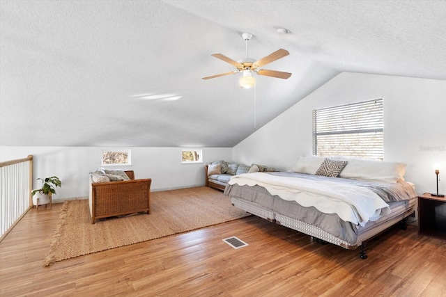 bedroom featuring wood-type flooring, lofted ceiling, ceiling fan, and a textured ceiling