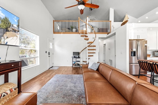 living room with visible vents, a ceiling fan, wood finished floors, high vaulted ceiling, and stairs