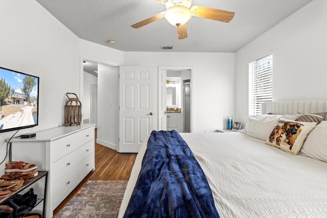 bedroom featuring ceiling fan, ensuite bathroom, and dark hardwood / wood-style flooring