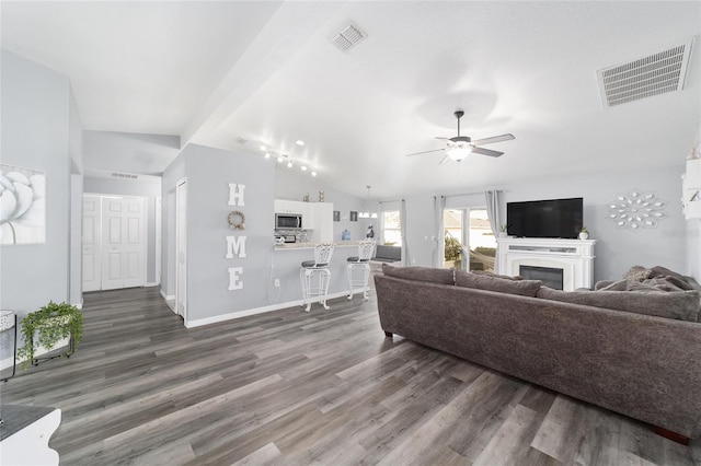 living room featuring ceiling fan, dark hardwood / wood-style flooring, and vaulted ceiling with beams