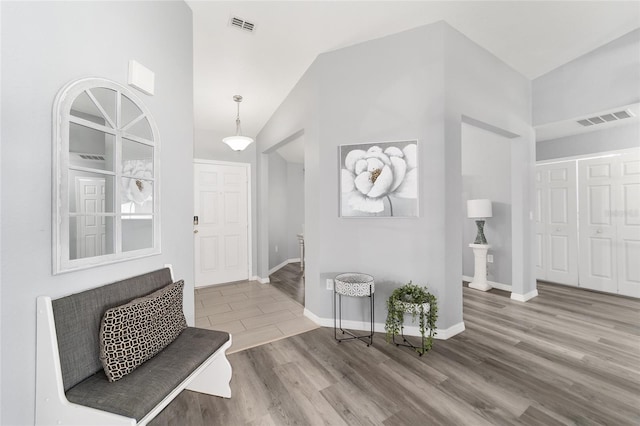 foyer featuring wood-type flooring and high vaulted ceiling