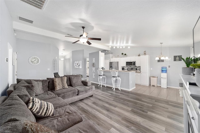 living room featuring light wood-type flooring, ceiling fan, and a textured ceiling