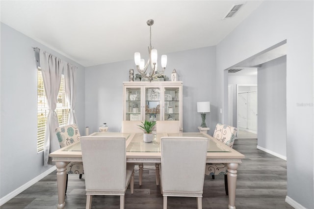 dining area with dark hardwood / wood-style flooring, a chandelier, and vaulted ceiling