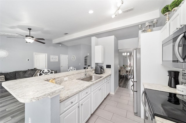 kitchen featuring ceiling fan with notable chandelier, white cabinetry, stainless steel appliances, sink, and kitchen peninsula