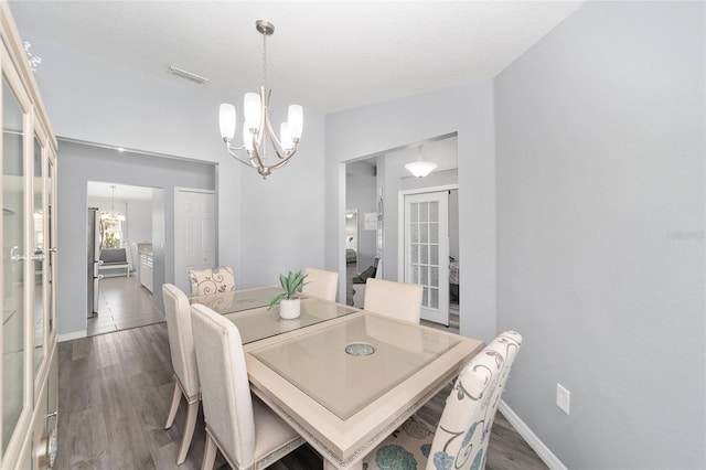 dining space featuring dark hardwood / wood-style flooring and an inviting chandelier