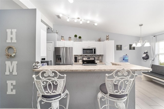 kitchen featuring white cabinets, a kitchen bar, appliances with stainless steel finishes, and tasteful backsplash