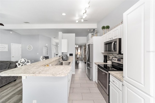 kitchen featuring kitchen peninsula, sink, white cabinetry, light tile patterned flooring, and stainless steel appliances