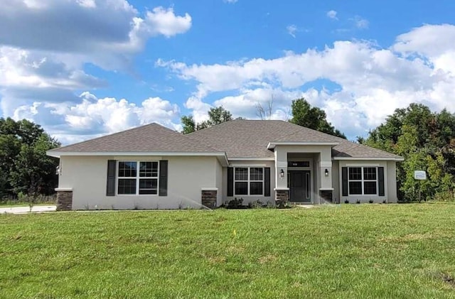 view of front of property featuring a front yard, roof with shingles, and stucco siding