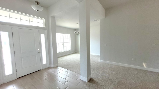 entryway with light carpet and a notable chandelier