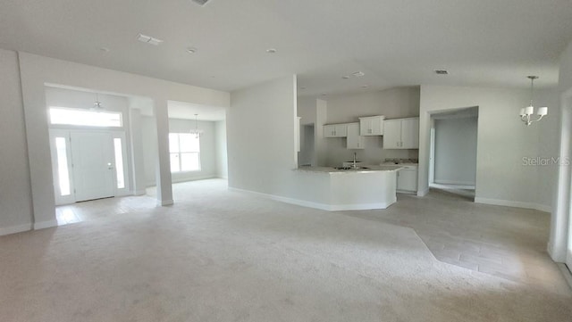 unfurnished living room featuring light carpet and a notable chandelier