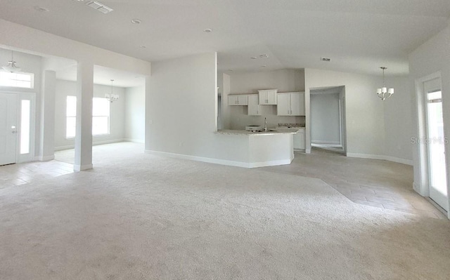 unfurnished living room with lofted ceiling, light colored carpet, a notable chandelier, and sink