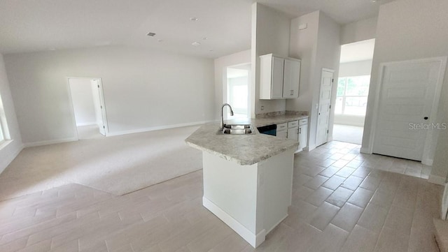 kitchen featuring sink, white cabinets, kitchen peninsula, and vaulted ceiling