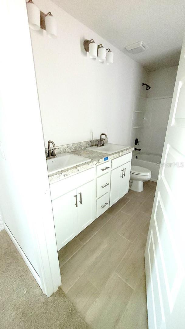 full bathroom featuring washtub / shower combination, toilet, and vanity