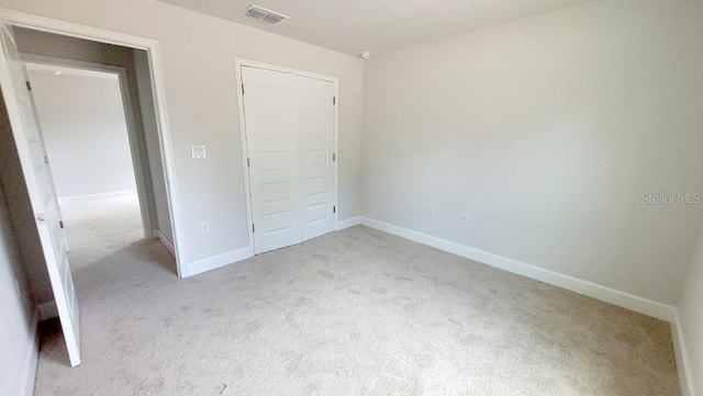 unfurnished bedroom featuring light colored carpet and a closet