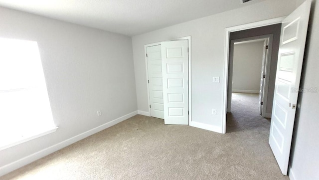 unfurnished bedroom featuring light carpet and a closet