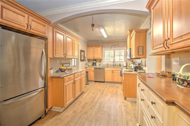 kitchen with appliances with stainless steel finishes, decorative light fixtures, light hardwood / wood-style floors, sink, and ornamental molding