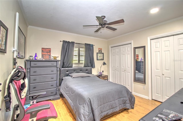 bedroom with ceiling fan, light hardwood / wood-style floors, two closets, and crown molding